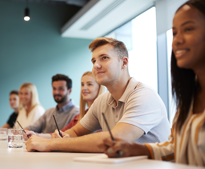 Photo of a group of young professionals listing to a trainer